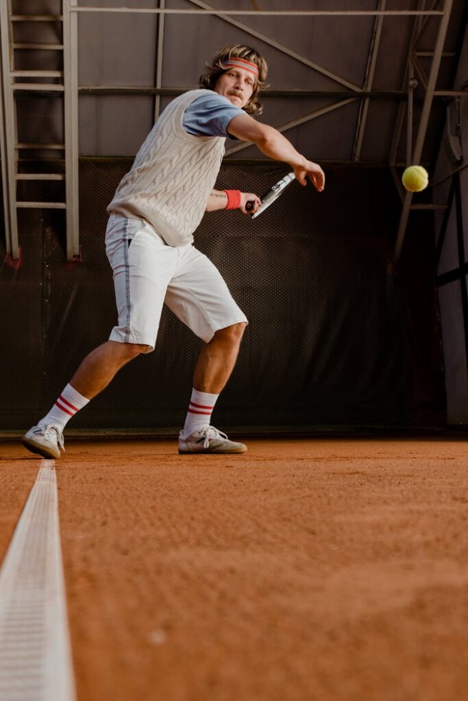 pexels-photo-5730291 A focused tennis player hits a ball on an indoor clay court, showcasing athleticism.